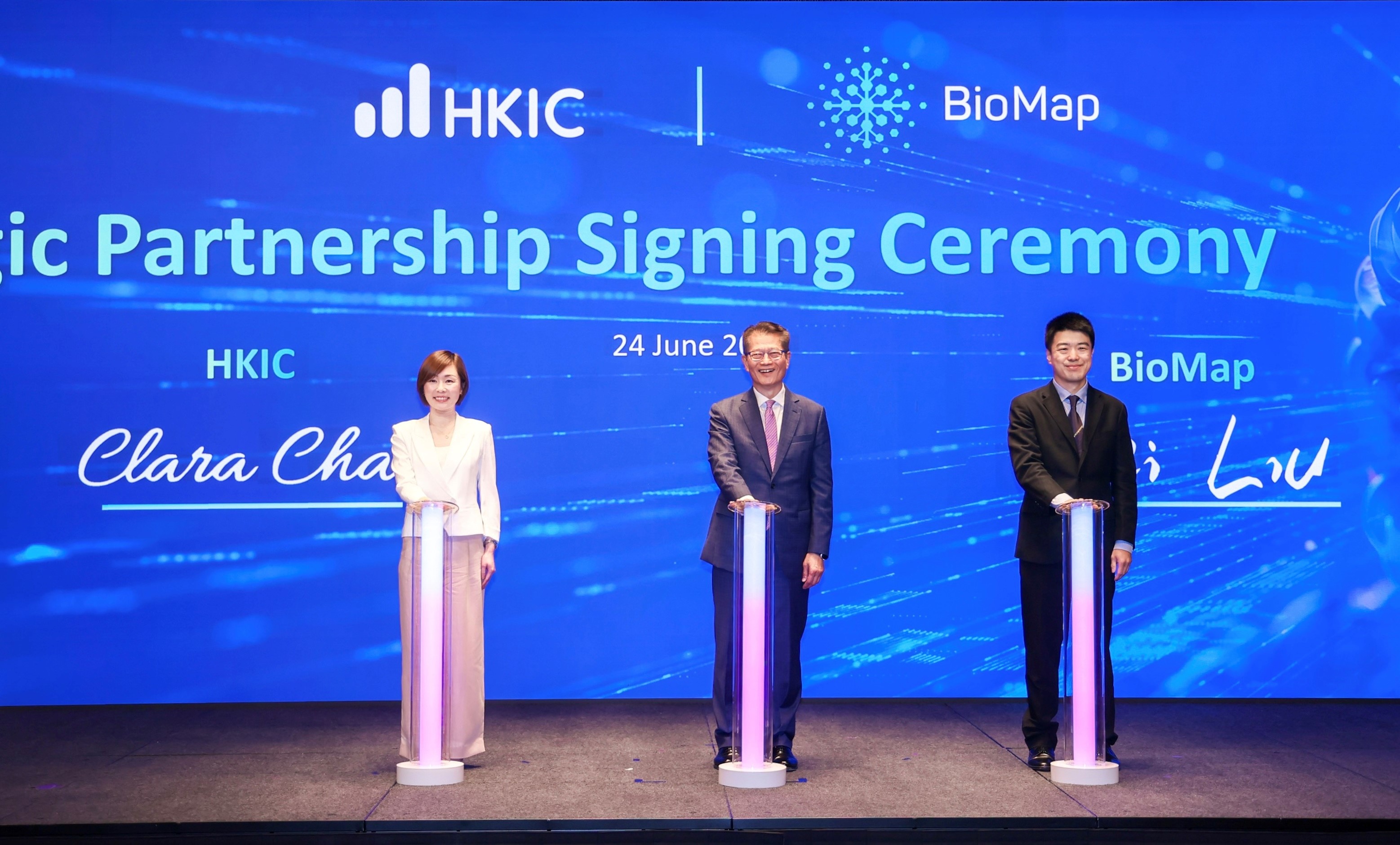 Clara Chan, CEO of HKIC (left), and Wei Liu, CEO of BioMap (right) signed the strategic partnership agreement, witnessed by Paul Chan, Financial Secretary of the Hong Kong SAR Government (centre).